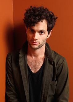 a man with curly hair is leaning against a wall