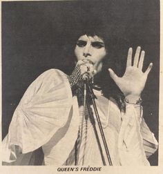 an old black and white photo of a person holding up their hand to the microphone