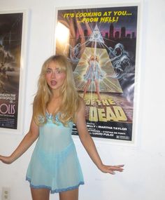 a woman standing in front of posters on the wall with her arms out and legs spread wide