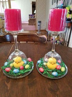 two candles sitting on top of a wooden table next to an egg nest with chicks in it