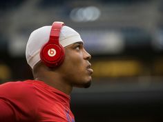 a close up of a person wearing headphones and looking off into the distance with a stadium in the background