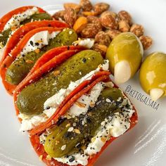 a plate topped with stuffed peppers and olives next to some nuts on the side