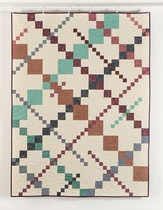 a quilt is hanging on the wall in front of a white frame with an image of squares and rectangles