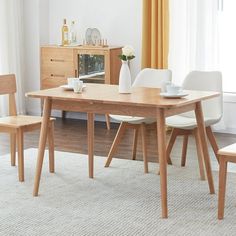 a dining table with two chairs and a vase on it in front of a window