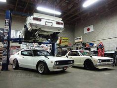 two cars are parked in a garage with one being lifted by a lift and the other is upside down