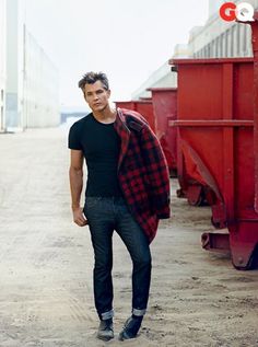 a man standing in front of a red dumpster with his hands in his pockets