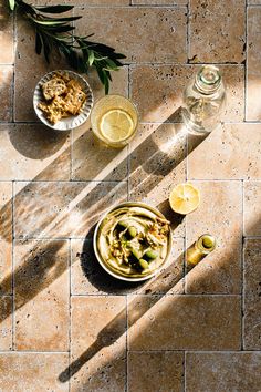 two bowls of food on a table with lemons and olives next to them