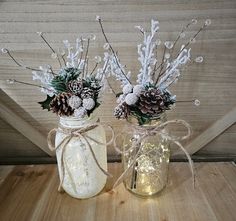 two mason jars filled with pine cones and flowers