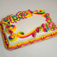 a decorated cake sitting on top of a white tablecloth covered in rainbow icing