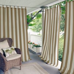 a chair sitting on top of a porch next to a window covered in striped curtains