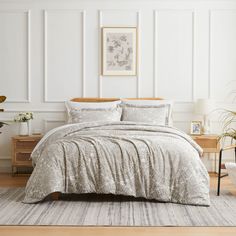 a bedroom with white walls and a bed covered in a silver comforter next to a wooden dresser