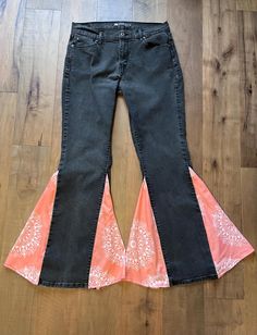 Take your denim game to the next level with these upcycled black Levi's straight-leg jeans, now transformed into stunning bell-bottoms. Featuring peach bandana print inserts, these jeans offer a bold pop of color and a unique retro twist to your wardrobe. Handcrafted with love and sustainability in mind, these bell-bottoms combine vintage inspiration with a modern boho-chic vibe. These jeans are a size 12 with a 32-inch inseam and a 41 1/2-inch outseam, perfect for those who love classic Levi's quality with an artistic upgrade. Whether you're headed to a festival or just looking to add some retro flair to your everyday wear, these one-of-a-kind jeans are made for you. Details: Size: 12 (Levi's straight-leg, upcycled) Color: Black with peach bandana print fabric inserts Material: Denim with Cotton Flare Jeans With Wide Leg For Festival, Cotton Wide Leg Flare Jeans For Festival, Bohemian Fitted Cotton Flare Jeans, Cotton Fitted Flare Jeans For Festivals, Fitted Cotton Flare Jeans For Festivals, Cotton Bohemian Flare Jeans, Bohemian Cotton Flare Jeans, Black Cotton Flare Jeans For Summer, Bohemian Flare Cotton Jeans