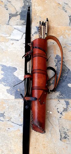 a leather case with several arrows attached to it sitting on the ground next to a pair of skis