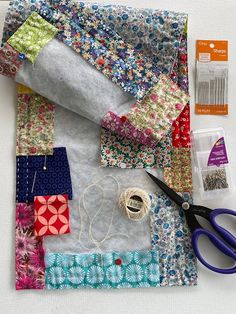 sewing supplies laid out on top of a piece of cloth with scissors, thread and pins