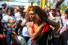 a woman with red curly hair is standing in front of a large group of people