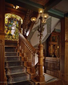 an ornate staircase with stained glass windows and chandelier in the center, along with wooden handrails