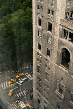 an aerial view of a city street with cars and people crossing the street in front of tall buildings