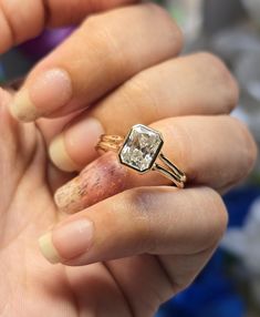 a woman holding an engagement ring in her hand, with the diamond on it's finger