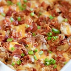 a casserole dish with bacon, cheese and green onions on it's side