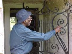 an old woman is opening the door to her home with wrought ironwork on it