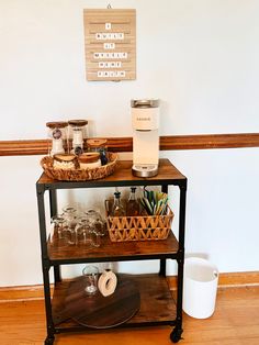 a wooden table topped with lots of glasses next to a shelf filled with wine glasses