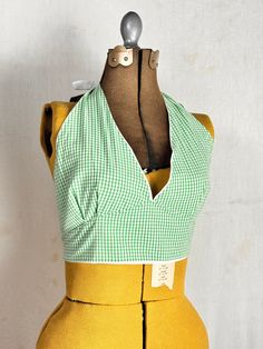 An authentic vintage halter tie top. woven gingham fabric. completely adjustable for best fit! a one of a kind homemade garment.  this is one of many tie tops we currently have available from one person's collection. see our other listings! era : 1970s material : cotton or cotton blend color : soft green, white condition : great, appropriate signs of age and wear as seen in photos size : one size fits many* , please compare measurements below *pictured on a dress form with a 36" bust, 30" underbust & has also been fitted on a dress from with a 41" bust , 33" underbust (not pictured) actual garment measurements : underbust : 53" including ties cup width : 8" cup length : 22" end of neck ties to band seam band width : 4" at wides point  - - - - - - - - - - - - - - - - - - - - - - - - - - - - Retro Fitted Tops For Picnic, Fitted Retro Tops For Picnic, Retro Fitted Gingham Tops, Tie Tops, Halter Tie Top, Green Gingham, Gingham Fabric, Dress Form, Tie Top