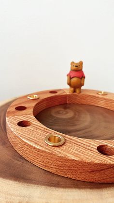 a wooden tray with holes in the middle and a small bear figurine on top