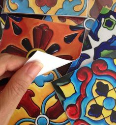 a hand holding a piece of paper near some colorful tiles