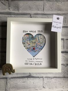 a white frame with a map in the shape of a heart and a wooden elephant figurine