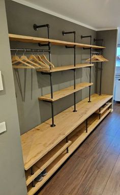 an empty walk in closet with wooden shelves and metal rails on the wall, next to a hardwood floor