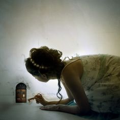 a woman kneeling down in front of a wall next to a jar with writing on it