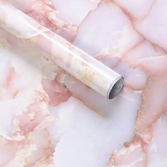 a pink and white marbled surface with a pen laying on it