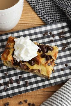 a piece of dessert sitting on top of a black and white checkered plate next to a cup of coffee