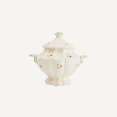 a white porcelain teapot with green and red designs on the front, sitting against a white background