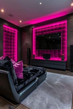 a living room filled with black furniture and pink lighting on the walls, along with a flat screen tv