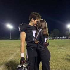 a man and woman standing next to each other on top of a field at night