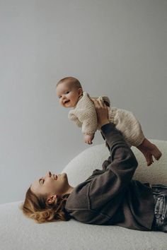 a woman laying on top of a bed holding a baby