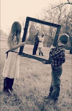 a little boy and girl standing in front of a mirror with their reflection on it