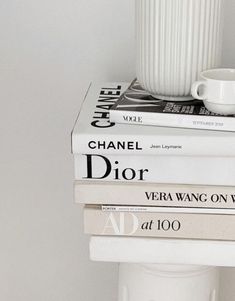 three books stacked on top of each other next to a white cup and saucer