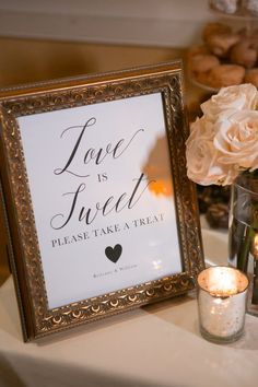 a framed sign sitting on top of a table next to a vase filled with flowers