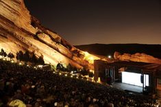 an outdoor movie theater is lit up at night in front of a large group of people