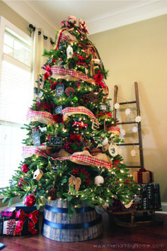 a christmas tree decorated with ribbon and ornaments in a living room area next to a window