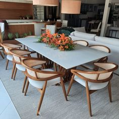 a table with chairs and flowers on it in the middle of a living room filled with furniture