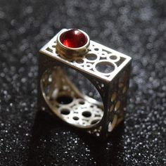 Discover the epitome of modern elegance with this handcrafted square silver ring, featuring a rich garnet centerpiece. The unique geometric design of this piece draws inspiration from contemporary architecture, offering a bold statement while maintaining a minimalist aesthetic. Each ring is meticulously crafted to highlight the natural beauty of the garnet, making it a perfect gift for those born in January or anyone who appreciates artisan jewelry. Add a touch of sophistication to any outfit with this distinctive ring. Modern Square Rings For Formal Occasions, Modern Red Rings For Formal Occasions, Modern Red Ring For Formal Occasions, Modern Garnet Rings For Formal Occasions, Modern Garnet Rings For Formal Events, Modern Red Ruby Ring For Wedding, Modern Red Ruby Wedding Ring, Contemporary Gemstone Rings For Gift, Contemporary Gemstone Rings For Gifts