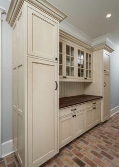 an empty kitchen with brick flooring and white cabinetry on the wall, along with a wooden counter top