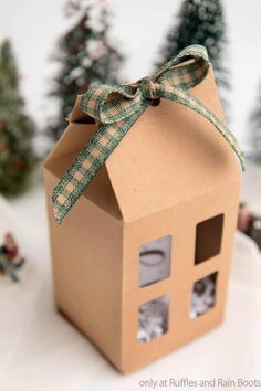 a cardboard box with a bow tied around the top that has pictures in it and trees