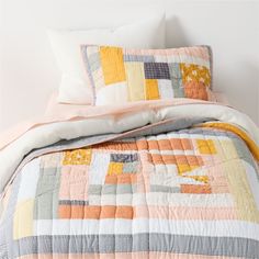 a bed with two pillows and a quilted comforter on top of the bed