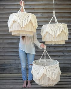 a woman is holding two white macrame lamps