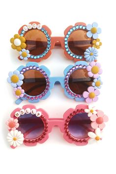 Handmade, one-of-a-kind personalized flower sunglasses for your kiddos. This item is made-to-order, so every single pair is truly unique. This style is available on flower or round shaped kid glasses. Please provide the name or word(s) for the glasses in the personalization field provided. The primary color choice is for the color of the sunglasses. Please specify in the personalization section if you have a specific rhinestone color request.  **SPECIAL REQUESTS* Please provide a note in the personalization field if you have any special requests, and we will do our best to accommodate them!  **LOCAL PICK UP / SHIPPING PROMOS** We do offer local pick-up for anyone willing to pick up from Mandeville, LA. Use promo code "LOCALPICKUP" at checkout to waive the shipping fee.  Shipping is free fo Fun Pink Handmade Sunglasses, Fun Handmade Pink Sunglasses, Handmade Fun Pink Sunglasses, Fun Handmade Sunglasses As A Gift, Fun Handmade Plastic Sunglasses, Handmade Plastic Fun Sunglasses, Handmade Fun Plastic Sunglasses, Trendy Handmade Pink Sunglasses, Playful Handmade Plastic Sunglasses