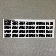 a black and white keyboard sticker sitting on top of a gray surface with the words made in china written across it